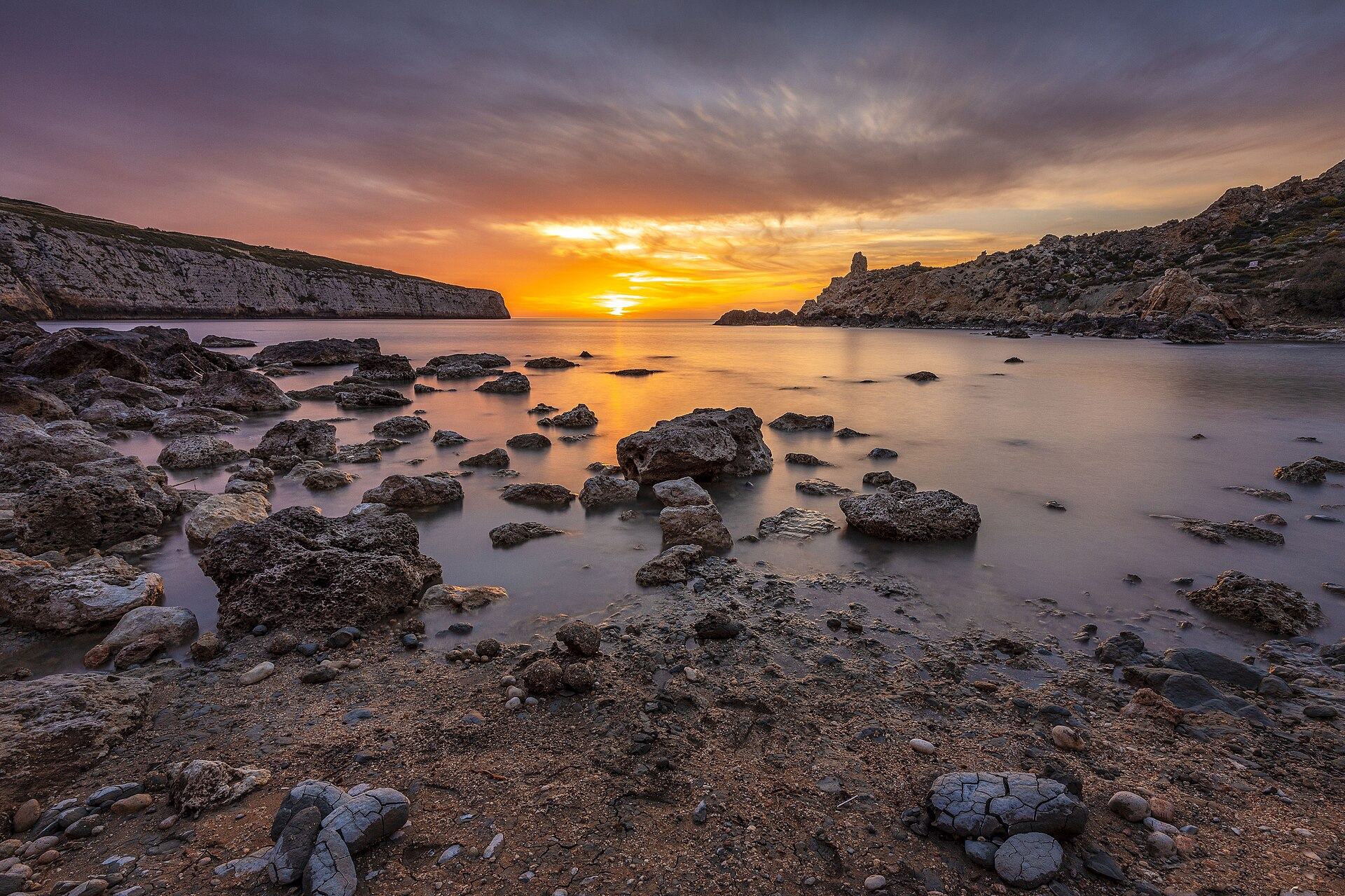 The undeveloped pebble shore and clay cliffs of Fomm ir-Riħ on Malta's west coast at sunset
