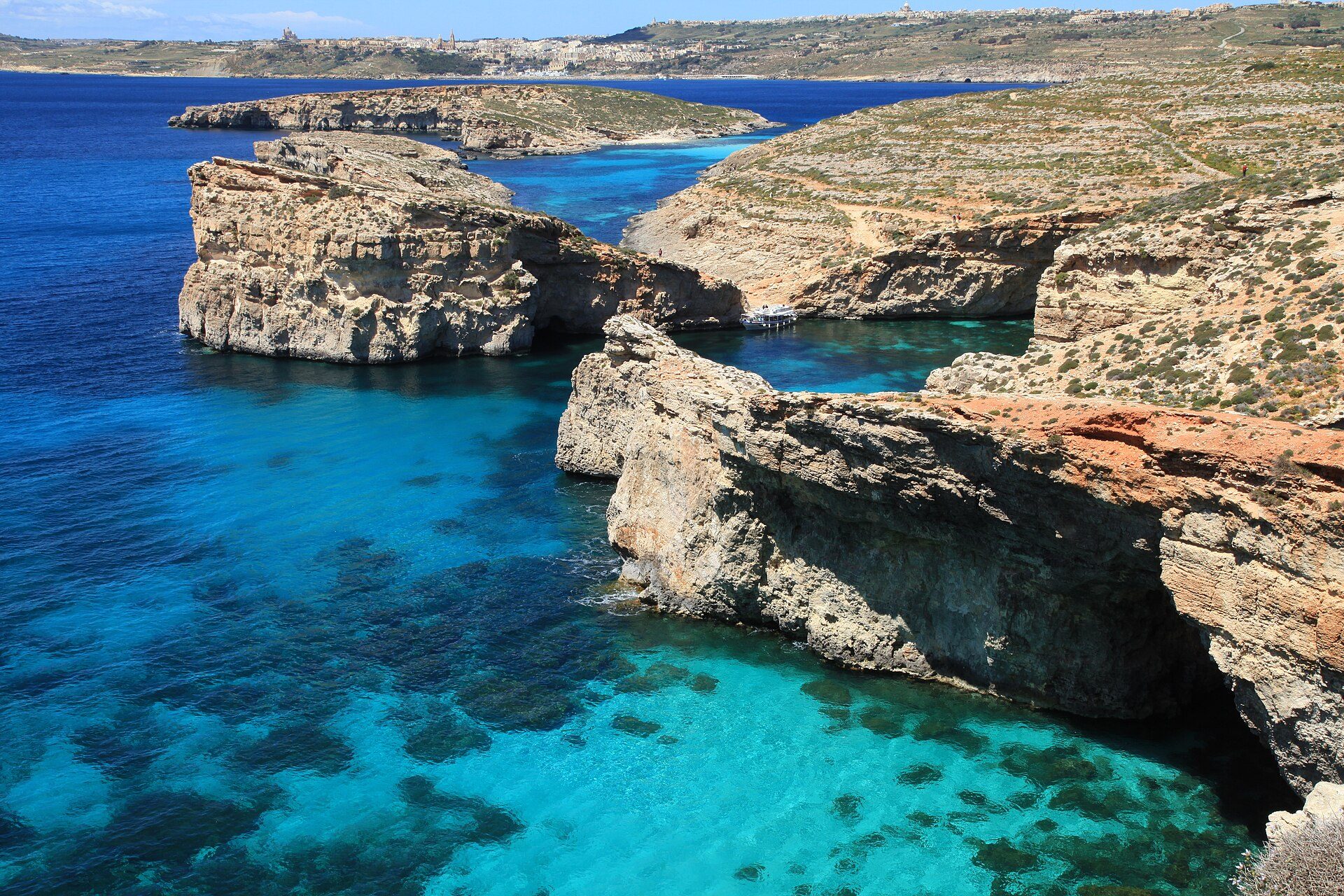 The Blue Lagoon between Comino and Cominotto — pale turquoise water over white sand, enclosed by low limestone headlands