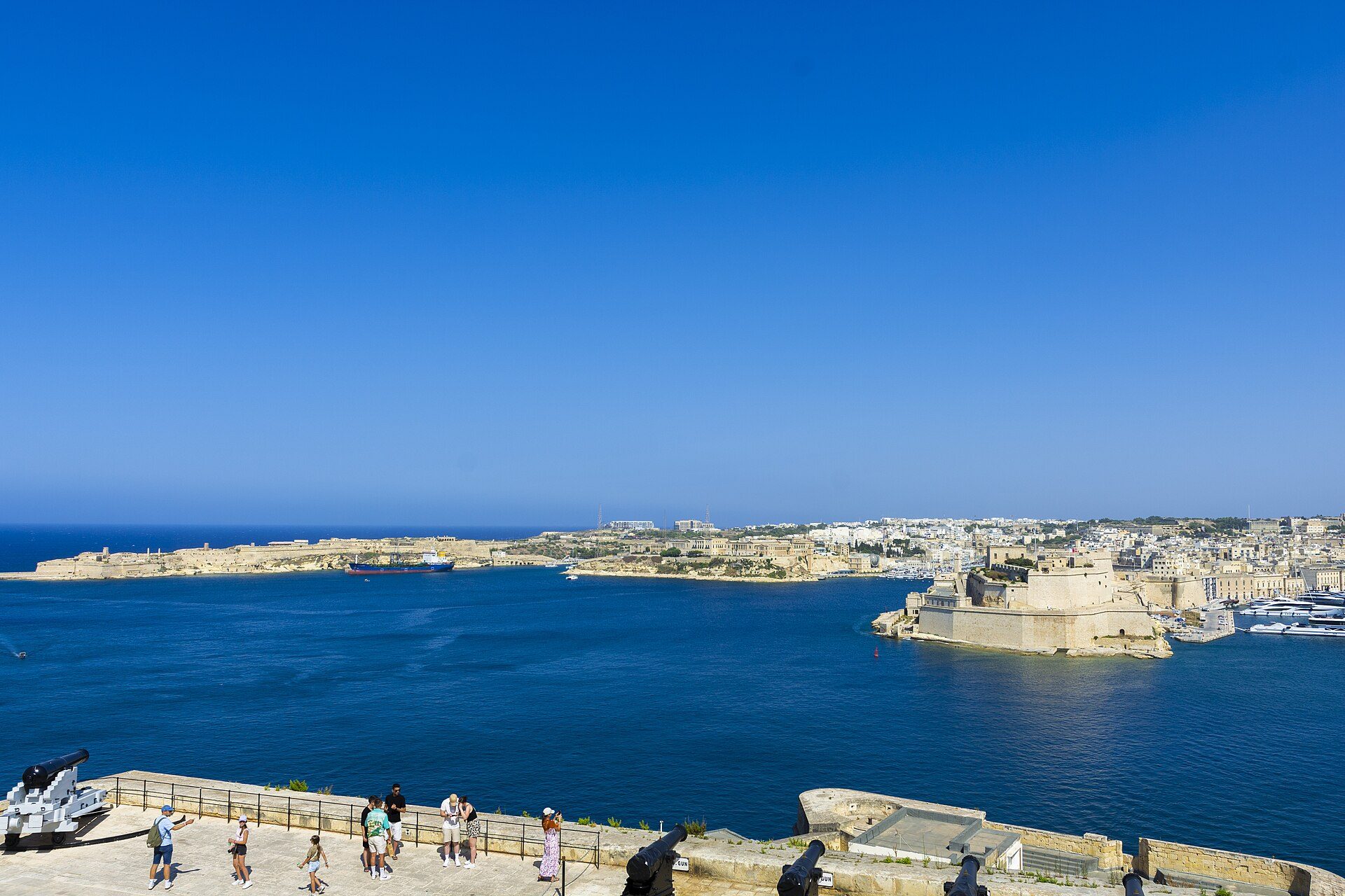 Grand Harbour seen from the Upper Barrakka Gardens in Valletta, with the fortified Three Cities on the opposite shore and boats on the water below.